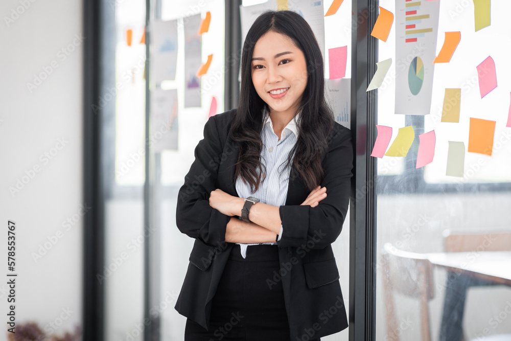 Young Serious Asian Creative team use post it notes to share idea sticky note on glass wall. Asian business people design planning and Brainstorming thinking sticky History notes concept.	