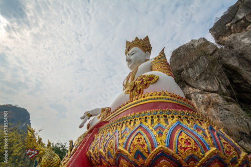 The white Buddha statue with rock mountain in the background at Tham Champathong monastery, Ratchaburi, Thailand photo