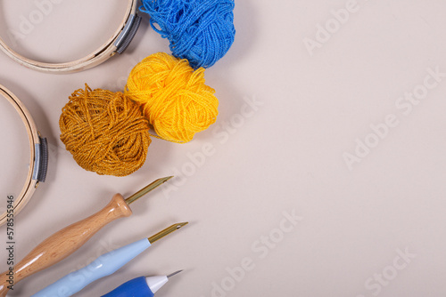 Material para bordar, aguja mágica, bastidor, madejas de lana color azul, amarillo y mostaza para crear punch needle, en superficie lisa neutra bordado colores vivos photo