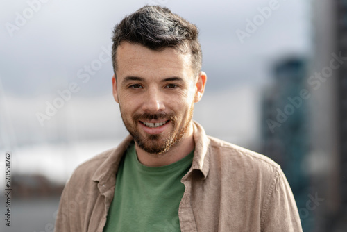 Authentic portrait of handsome smiling hispanic man wearing casual clothing looking at camera standing on the street