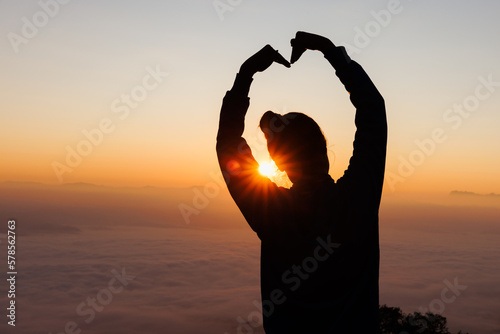 Hands in shape of love heart, Female hands in the form of heart against the sky pass sun beams. Happy in love.