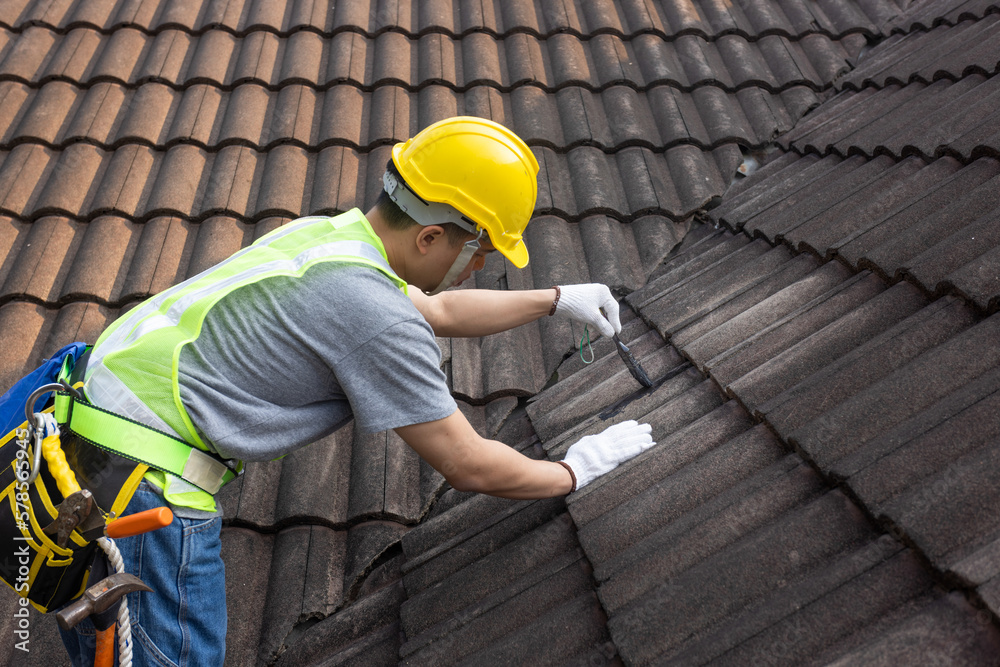 Worker man using waterproof roof coating repair to fix crack of the old tile roof. - obrazy, fototapety, plakaty 