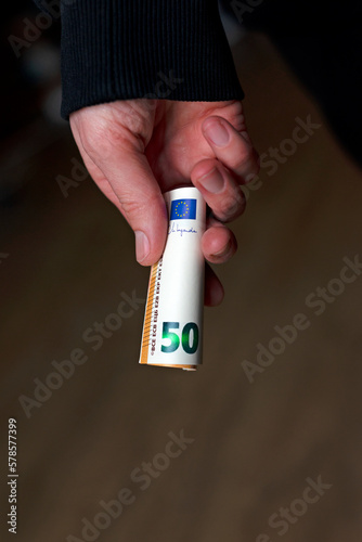 Obraz na płótnie Rolled euro money in hand on a dark background. w salonie