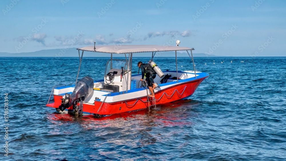 An unidentied resort boatman loads air tanks into the boat in preparation for the next group scuba dive, in the Philippines.