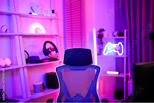 Gamer ergonomic chair with remote controller car, wireless VR and entertainment gadget in neon light room