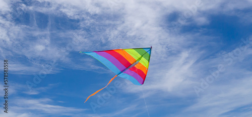 rainbow kite flying against a blue sky.