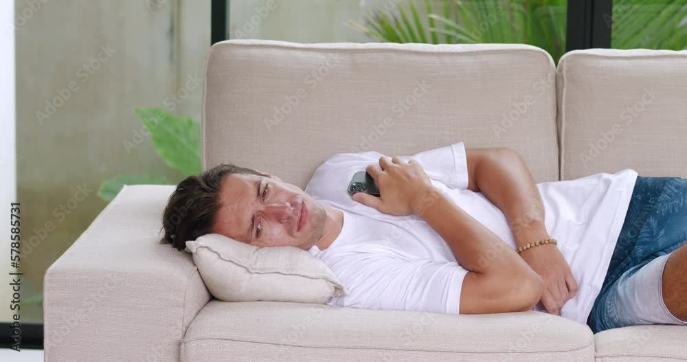 Upset man reads message on smartphone about bad news he was dumped by girlfriend. Portrait male millennial lying on couch, suffering from relationship problems. Concept of man abandoned by girlfriend