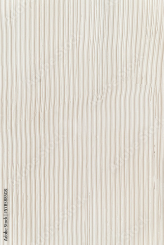 Surface of the wall with a decorative white plaster. Textured concrete wall with vertical lines.
