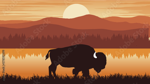 a bison is standing near a lake with mountains