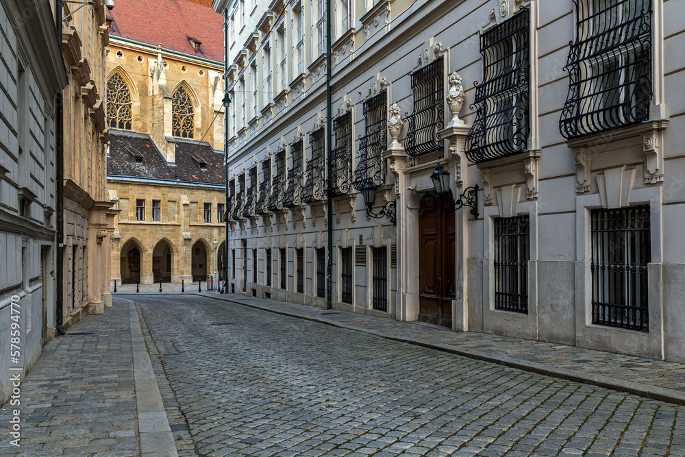 Narrow cobblestone street among historic buildings in historic center of Vienna.