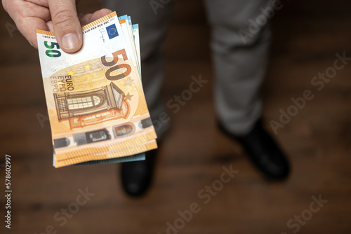 Well dressed man holding in the hand or giving bunch of money, euro banknotes, European Union paper currency