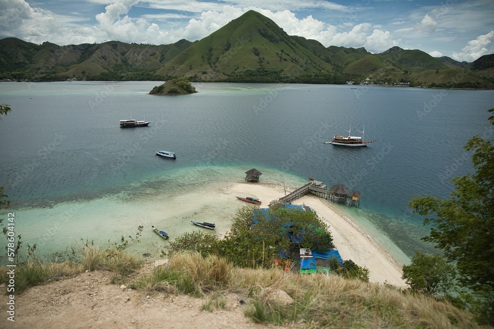 Idlillic panorama shot from the top of the hill of Kalor Island in Komodo National Park on Flores, below the beach, in the background hills and the sea.