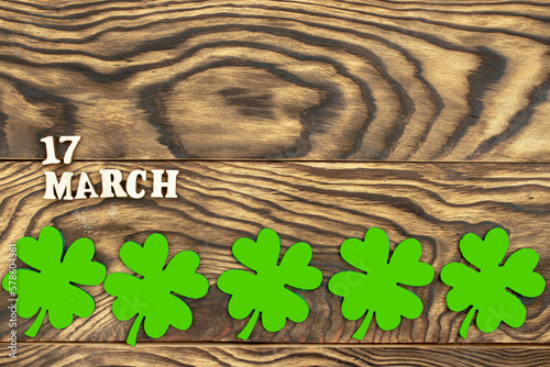 The inscription March 17 and a clover leaf on a dark wooden background. The concept of celebrating St. Patrick. Blank for congratulations on St. Patrick's Day. copy space. Flat layout.