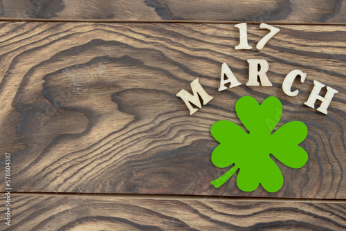The inscription March 17 and a clover leaf on a dark wooden background. The concept of celebrating St. Patrick. Blank for congratulations on St. Patrick's Day. copy space. Flat layout.