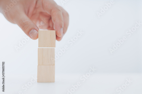 Businessman putting three wooden blocks on top