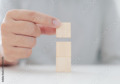 Businessman putting three wooden blocks on top