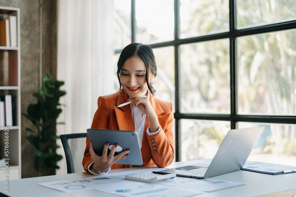 Fototapeta premium Young beautiful woman using laptop and tablet while sitting at her working place. Concentrated at work. in office..