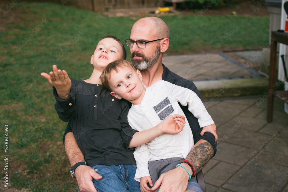 A happy father holds his two small children in his lap A happy father holds his two small children in his lap