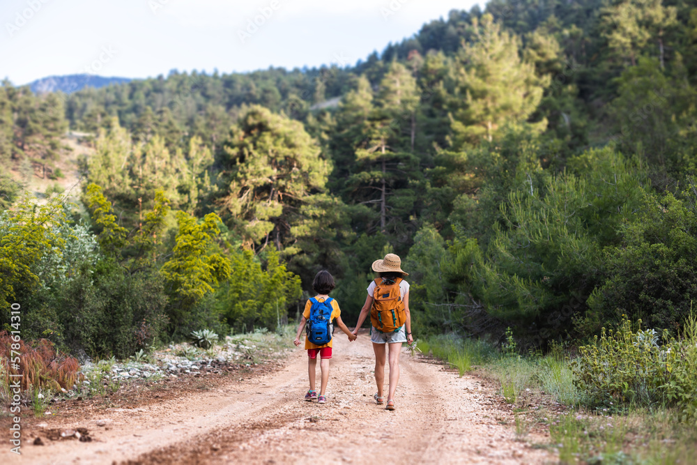 A child with mom walks along a forest path