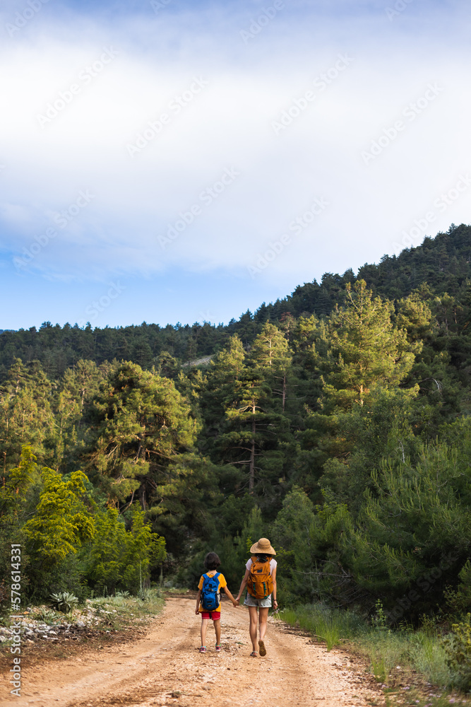 A child with mom walks along a forest path A child with mom walks along a forest path