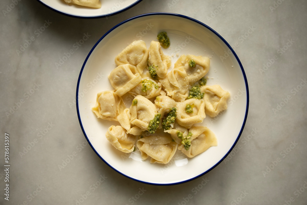 ready hot ravioli with pesto sauce and grated cheese on a white plate close-up. dumplings ready to eat ready hot ravioli with pesto sauce and grated cheese on a white plate close-up. dumplings ready to eat