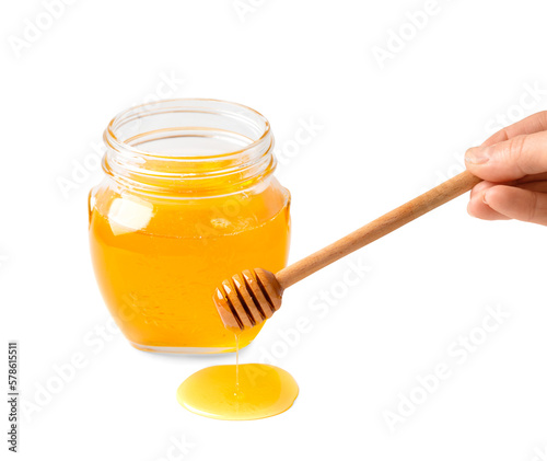 Honey in glass jar and dipper on white background