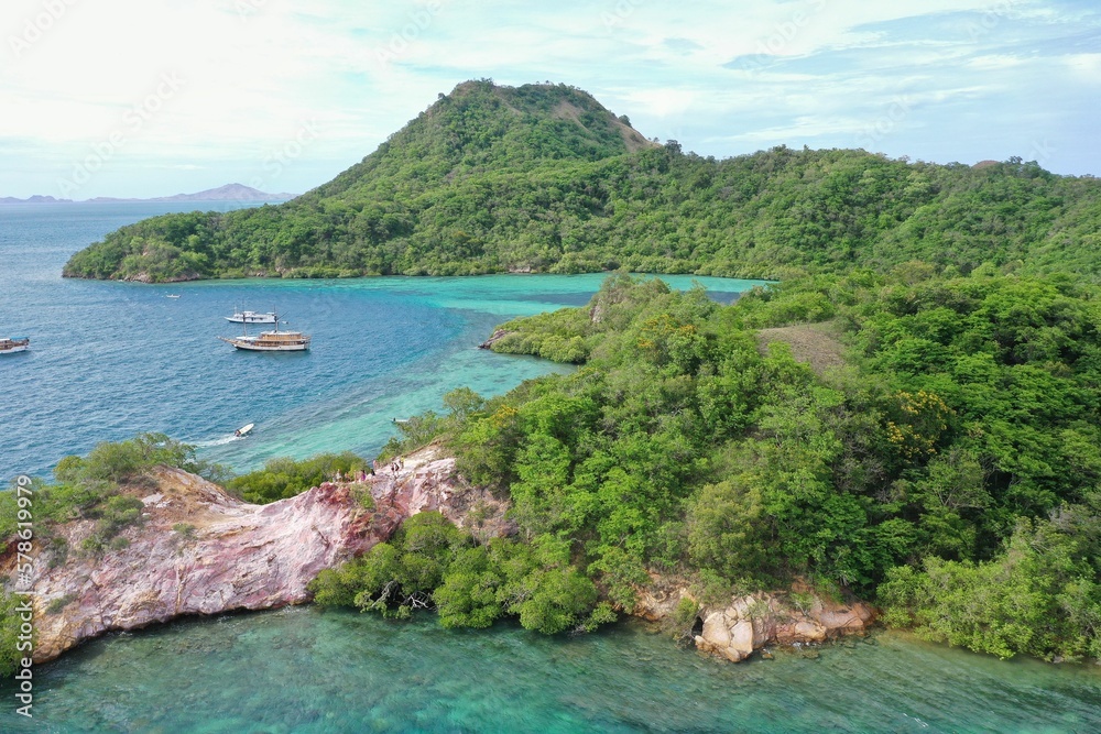 Idyllic panorama of a bay in Komodo National Park on Flores with turquoise sea with boats and green hills.