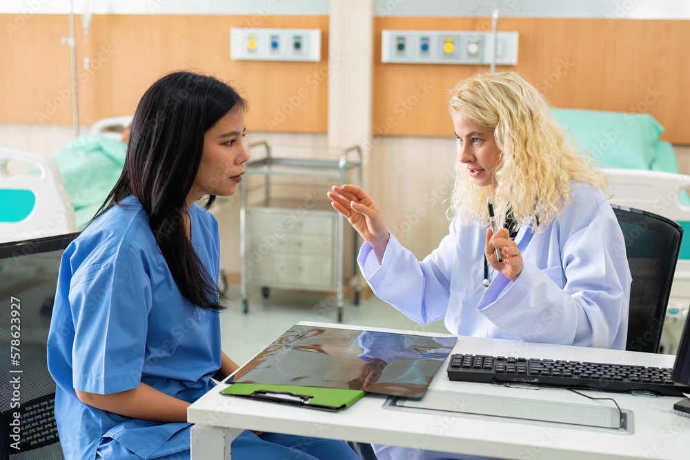 Obraz premium Young female doctor discus with lady patient on chest x-ray at hospital clinic