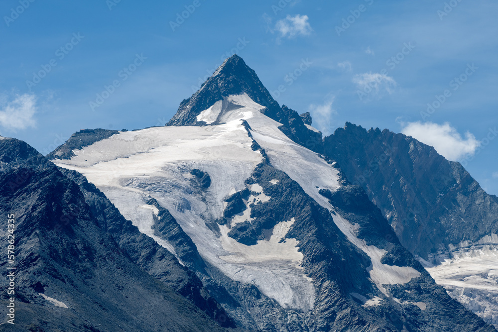 Mountain peak with a melting glacier on brown and grey rocks in an alpine area