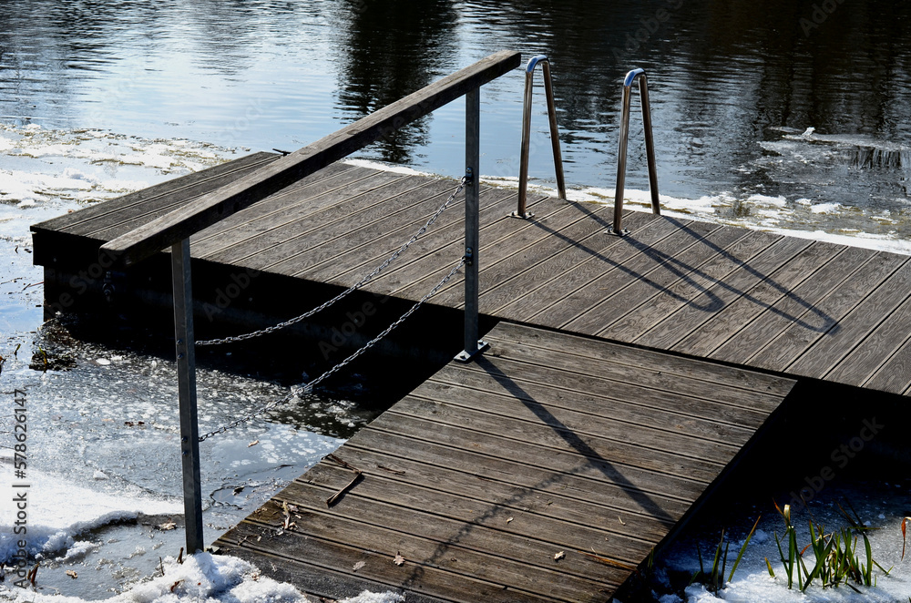 Fototapeta premium frozen river has modified entrances to water from embankment. swimmer decides to take a bath as part of conditioning and hardening after sauna, it is possible to use stainless steel steps, ladder