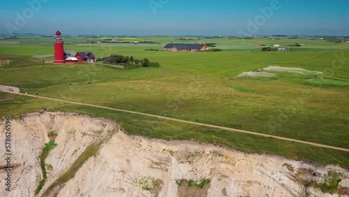 View of the red lighthouse Bovbjerg Fyr and cliffs at the danish coast. Footage of beautiful nature landscape Danish North Sea coast, Jutland, Denmark, Europe. Fly away drone fligth from lighthouse. photo