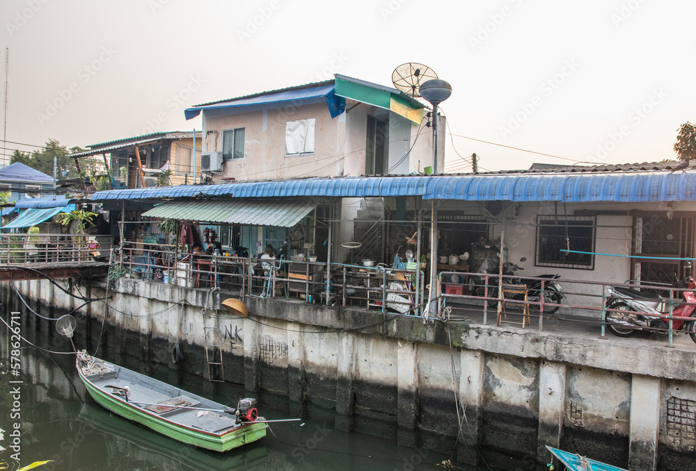 A klong or river channel with fishing boats, buildings and house fronts in Thailand Asia