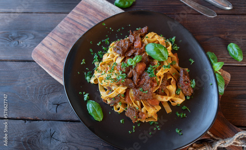 Pasta with Beef meat on a plate isolated on dark wooden background with copy space