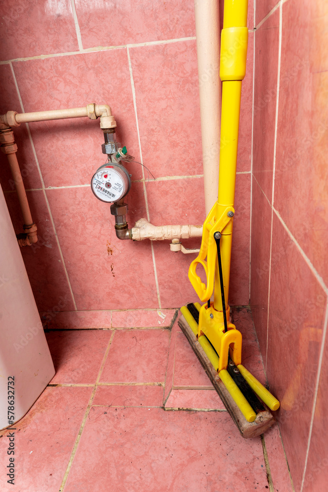 old water pipes with a utility water meter. an old dirty bathroom Stock