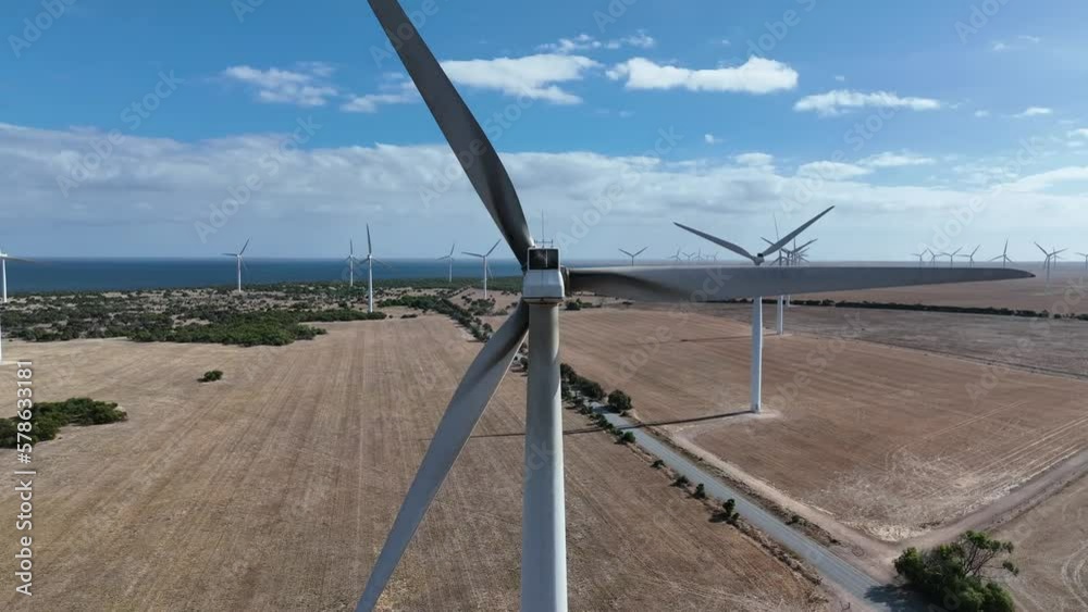 Ascending drone shot of spinning Wind Turbine. Camera flys up to a top down shot looking directly down onto the wind turbine. Shot in South Australia, with the ocean and farmland in the background. Ascending drone shot of spinning Wind Turbine. Camera flys up to a top down shot looking directly down onto the wind turbine. Shot in South Australia, with the ocean and farmland in the background.