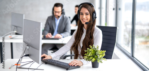 Obraz na płótnie Online helpdesk worker in hands-free headset using computer in office.