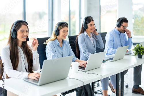 Group of friendly customer support operators working at call center.