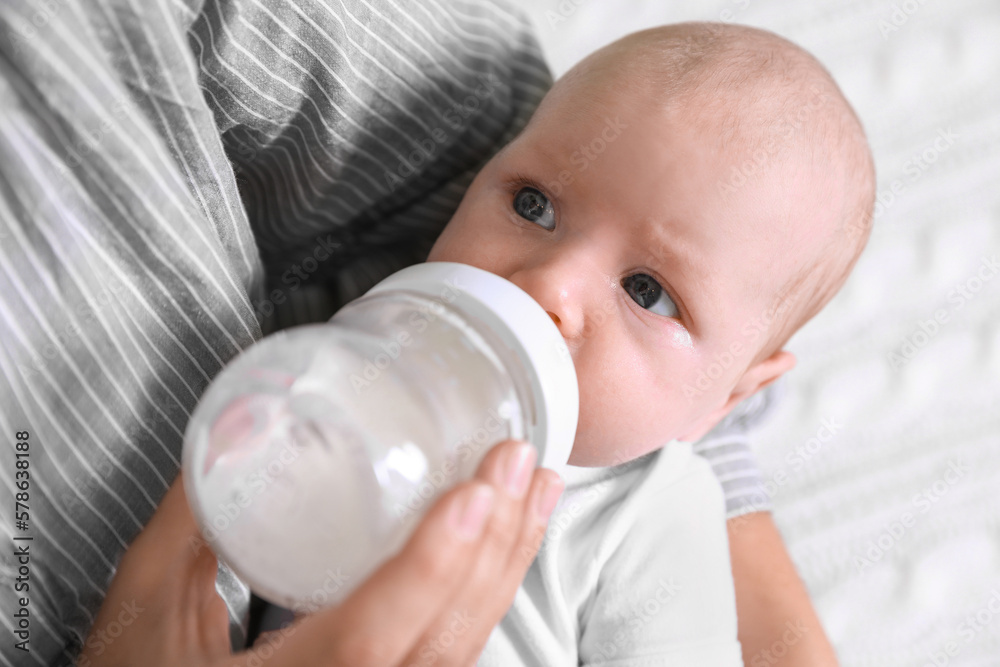 Mother feeding her little baby from bottle, closeup Mother feeding her little baby from bottle, closeup