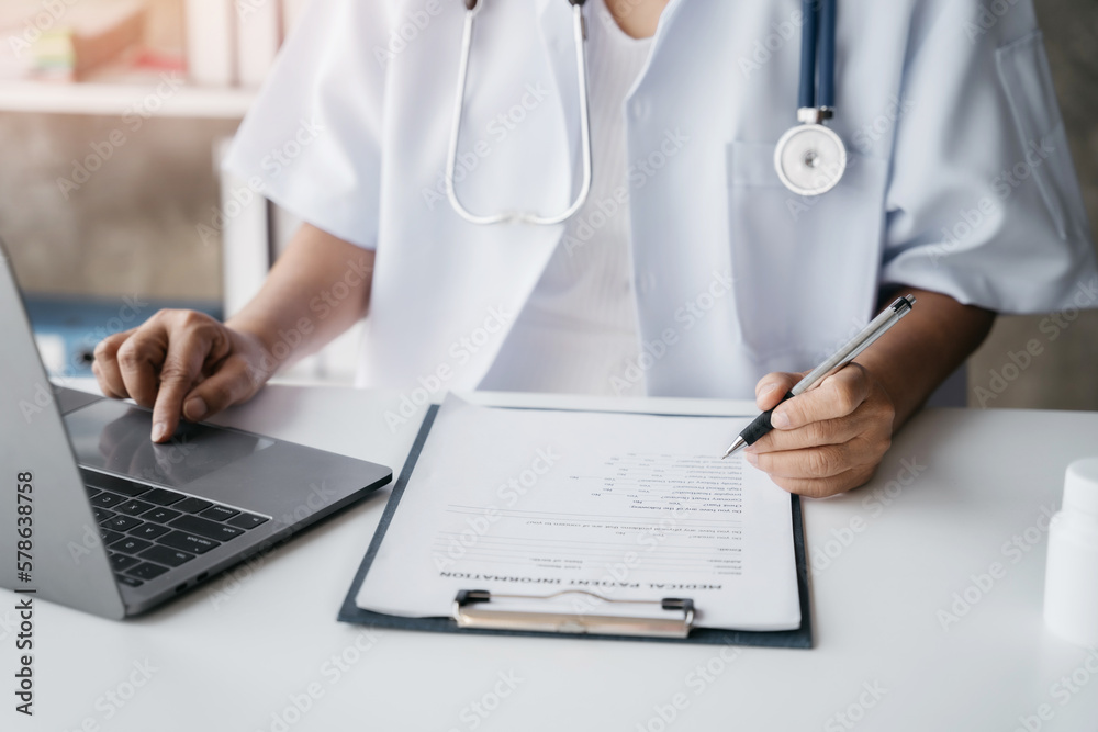 Doctor working on laptop computer and tablet and medical stethoscope on clipboard on desk, electronics medical record system EMRs concept. Doctor working on laptop computer and tablet and medical stethoscope on clipboard on desk, electronics medical record system EMRs concept.