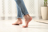 Barefoot woman walking on white parquet at home, closeup. Heated floor