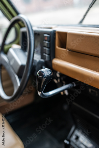Selective focus on the dashboard-mounted shift lever in an old French vehicle with the steering wheel and dashboard in the background