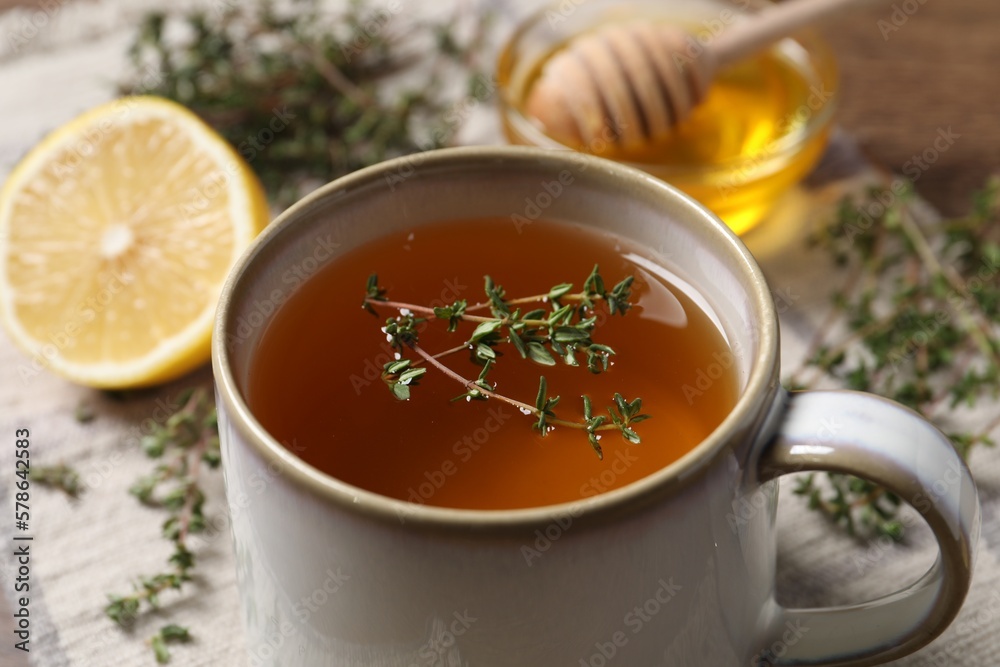 Cup of aromatic herbal tea with thyme on table, closeup
