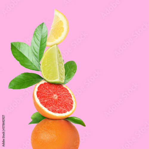Fototapeta Naklejka Na Ścianę i Meble -  Stack of different fresh citrus fruits with green leaves on pink background, space for text