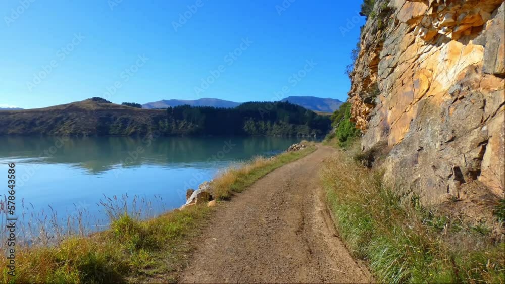 Walking on coastal track in harbor beside interesting wall of volcanic rock on a beautiful day - Governors Bay Track, Banks Peninsula (New Zealand) Walking on coastal track in harbor beside interesting wall of volcanic rock on a beautiful day - Governors Bay Track, Banks Peninsula (New Zealand)