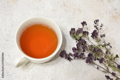 A cup of tea next to a bunch of dry lavender flowers isolated on marble background 