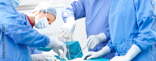 My work takes lots of focus. Profile shot of surgeons working together wearing scrubs in an operating room.