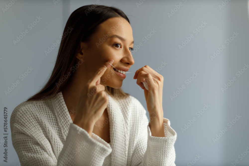 Portrait of attractive smiling young woman engaged in everyday procedures after shower. Brushing your teeth, flossing your teeth. Snow-white smile, wink with his eyes. Care, beauty and health. Portrait of attractive smiling young woman engaged in everyday procedures after shower. Brushing your teeth, flossing your teeth. Snow-white smile, wink with his eyes. Care, beauty and health.
