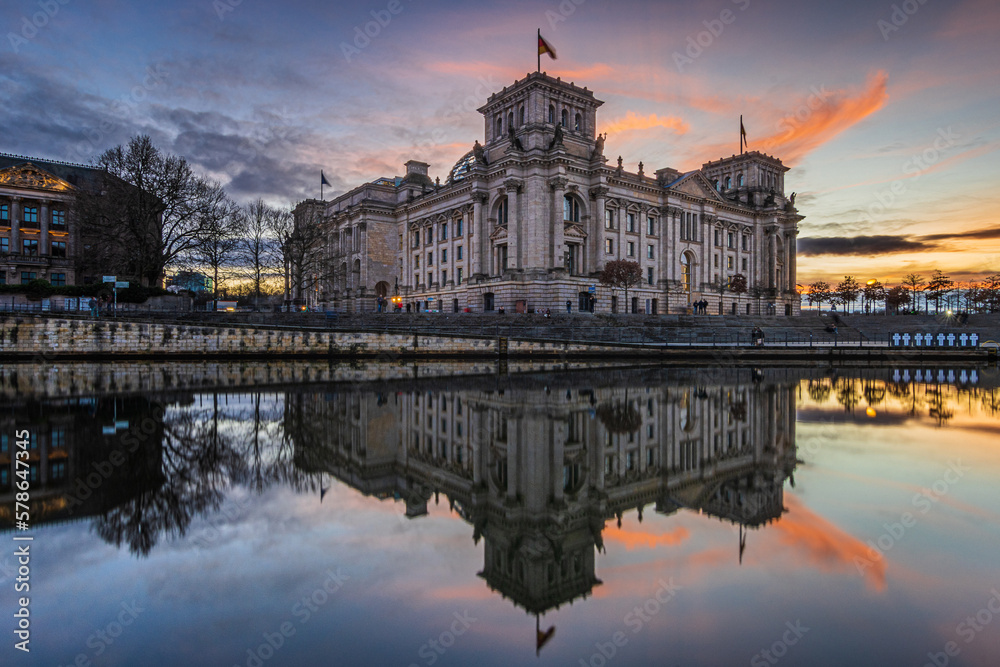 View of the parliament building in Berlin. Government in Germany at the Republic Square. River Spree with sunset reflection. Illuminated historical building in the evening. colored clouds in the sky