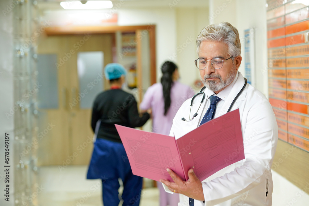 Indian senior doctor watching medical report at hospital. Indian senior doctor watching medical report at hospital.