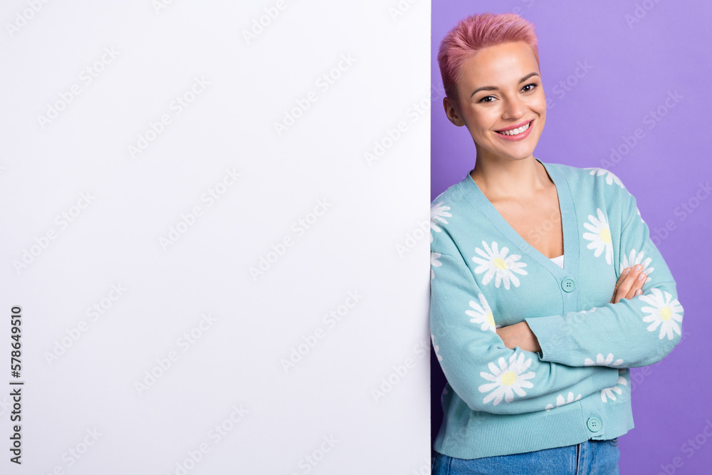 Photo portrait of satisfied smiling woman dyed pink hair folded arms wear blue print cardigan near paper banner isolated on violet color background Photo portrait of satisfied smiling woman dyed pink hair folded arms wear blue print cardigan near paper banner isolated on violet color background